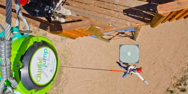 overhead view of QUICKjump Free Fall Device with woman jumping off tower connected to free fall device with fall attenuation surface at the bottom